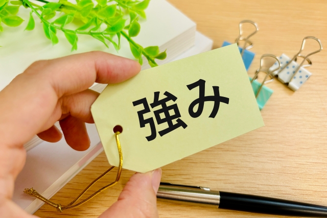 「強み」と書かれたタグを持つ手
