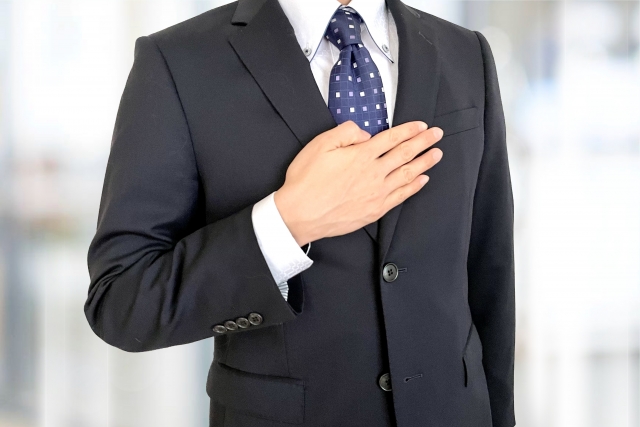 胸に手を当てるスーツ姿の男性