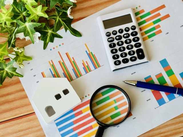 グラフ資料と電卓・住宅模型のイメージ