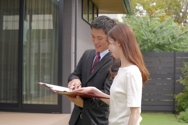 戸建て住宅の査定をしている営業マン